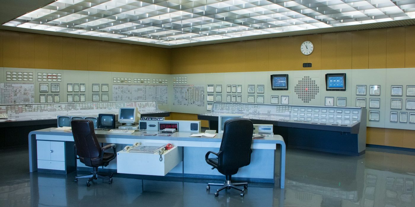 A modern control room with operator desks and wall-length control panels